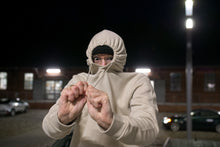 Load image into Gallery viewer, Stefan Kuhnigk wearing the thecoffeemonsters &quot;19 &quot;Angry Chicken&quot; crema standard hoodie&quot; at night in a carpark, pulling the roped of the hood.
