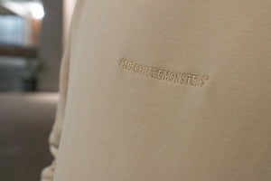 Closeup of the embroidery of thecoffeemonsters logo on the "19 "Angry Chicken" crema standard hoodie"