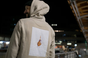 Stefan Kuhnigk wearing the thecoffeemonsters "19 "Angry Chicken" crema standard hoodie" at night in a carpark, seen from behind, backprint visible, wearing the hood, smiling.